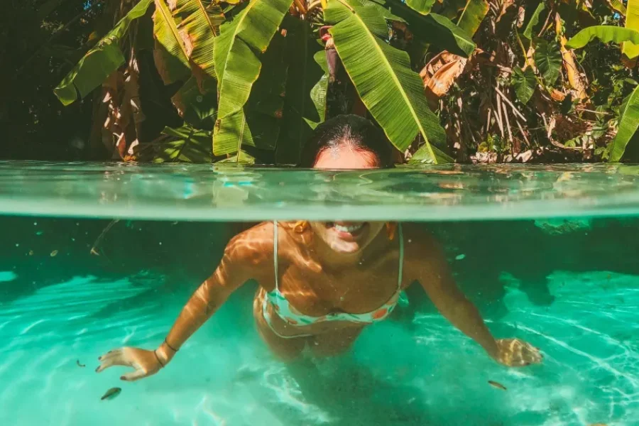 Woman swimming in a crystal-clear natural spring (fervedouro) surrounded by tropical vegetation, Jalapão, Tocantins, Brazil