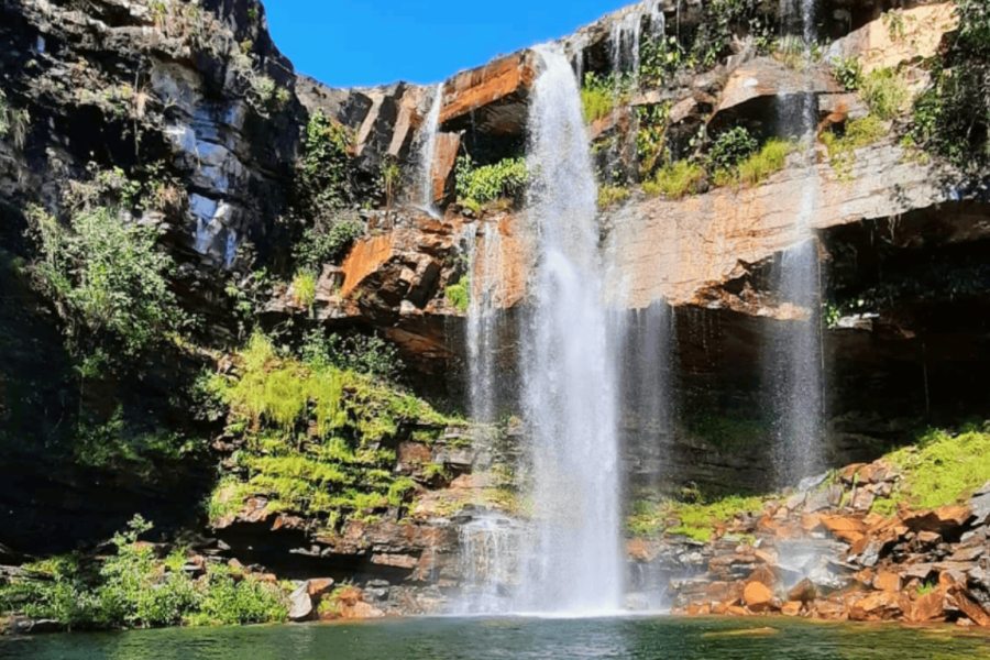 Cordovil Waterfall in Chapada dos Veadeiros, with water cascading down a rocky cliff and a crystal-clear pool surrounded by native cerrado vegetation.