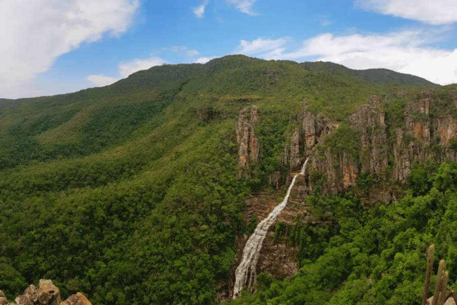 Panoramic view of the Sertão Zen Waterfall in Chapada dos Veadeiros, with a cascade framed by rocky cliffs and native cerrado vegetation.