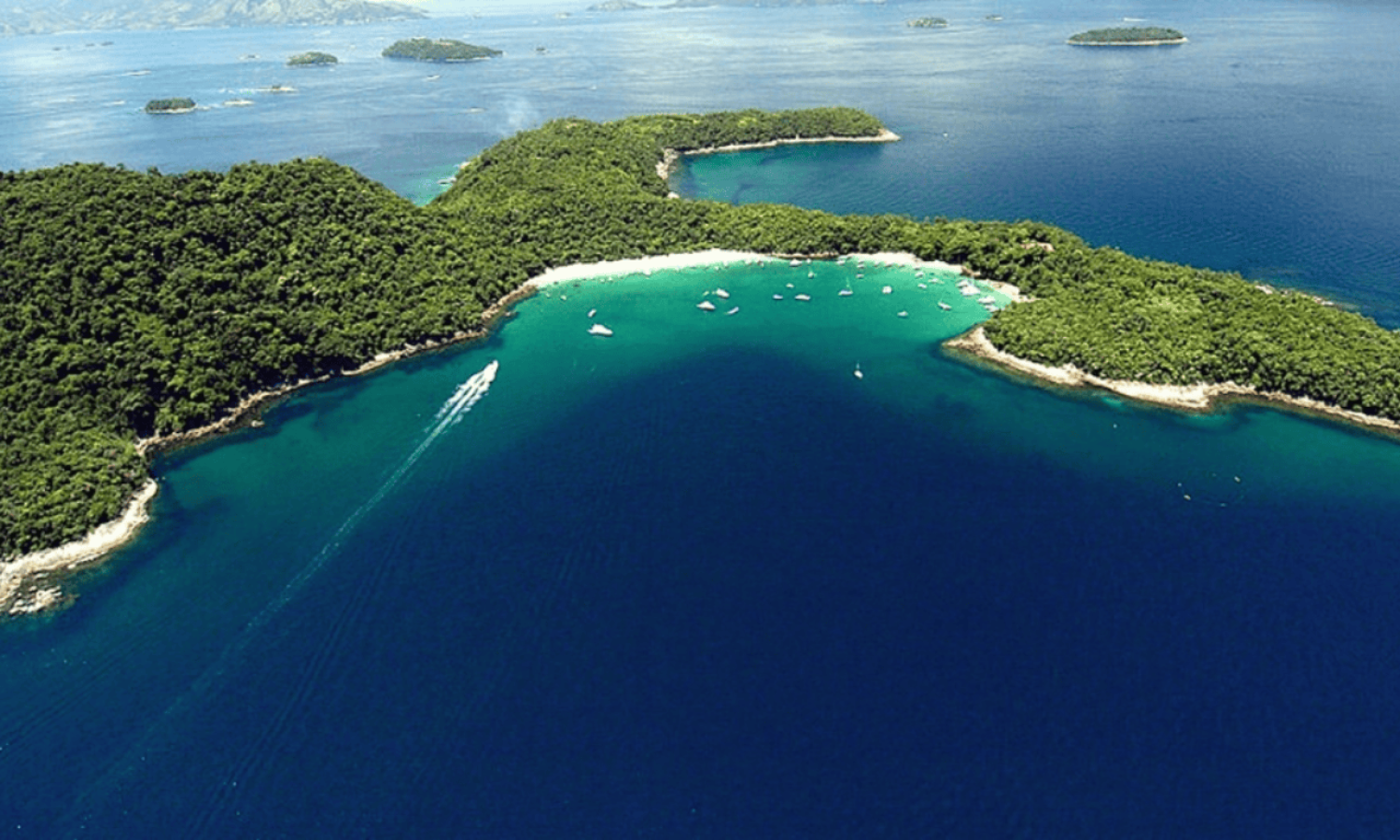 Aerial view of the Tamoios Environmental Protection Area in Angra dos Reis, featuring islands covered in Atlantic Forest, turquoise-blue waters, and boats resting in a preserved cove.