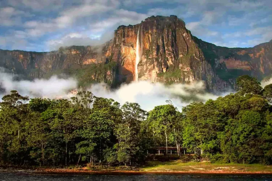 Imponente tepuy de paredes rocosas verticales con una cascada que cae por el acantilado, envuelto en niebla y rodeado de densa selva tropical, en la región del Monte Roraima, Venezuela.