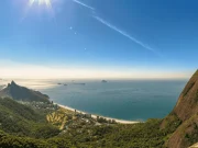 Vista panoramica dalla Pedra Bonita sulla spiaggia di São Conrado, la Barra da Tijuca, il Morro Dois Irmãos e l'oceano Atlantico, con la Foresta di Tijuca che incornicia il paesaggio sotto un cielo azzurro, a Rio de Janeiro, Brasile.