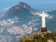 Il Cristo Redentore a braccia aperte in cima al Corcovado, con la città di Rio de Janeiro e il Pan di Zucchero sullo sfondo, visto dalla Foresta di Tijuca, Rio de Janeiro, Brasile.