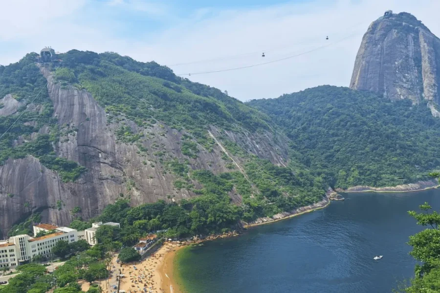 View of Sugarloaf Mountain and Morro da Urca from Morro da Babilónia, with the cable car in motion, Praia Vermelha and Guanabara Bay in the background, in Rio de Janeiro, Brazil.