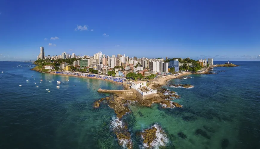 Vista aérea de Salvador com a praia da Barra, o farol e o casario do litoral sobre o mar turquesa, Bahia