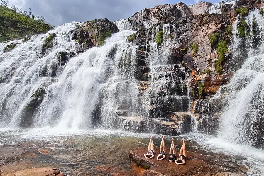 Cataratas dos Couros waterfalls in the Chapada dos Veadeiros, with people resting on the rock beside the falls